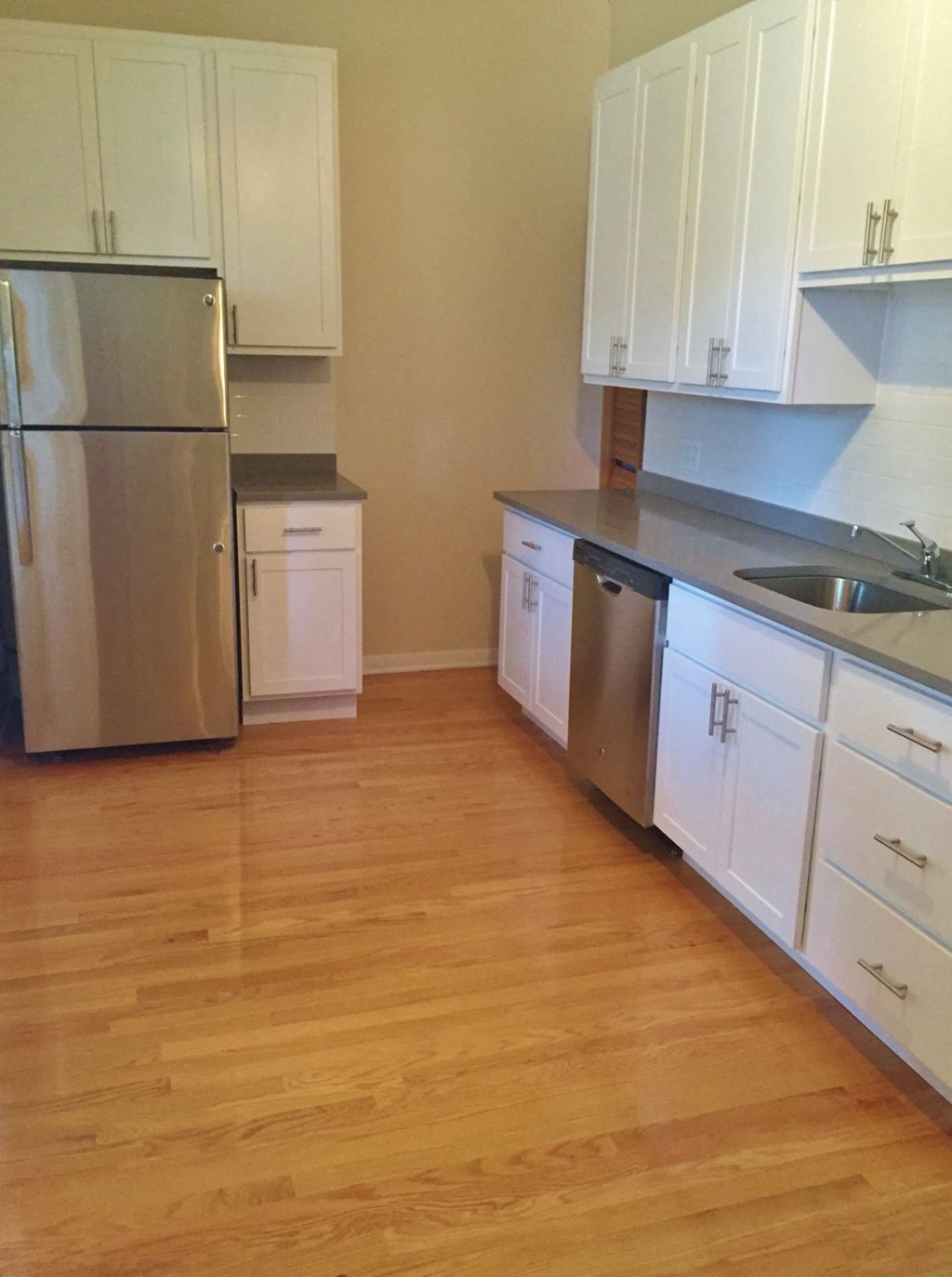 a kitchen with white cabinets and a stainless steel refrigerator
