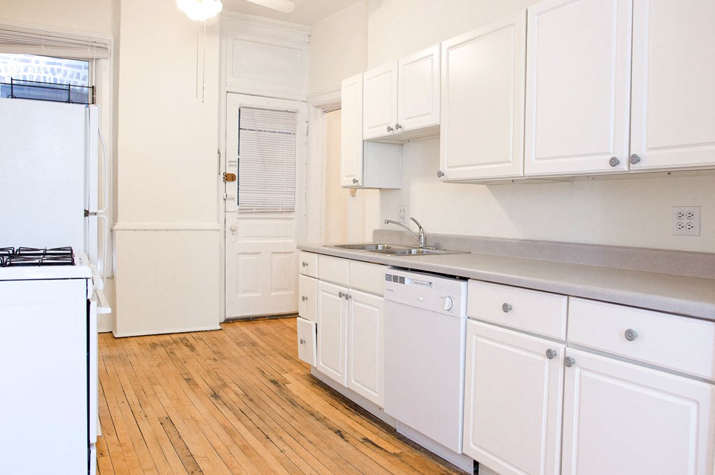 a kitchen with white cabinets and a sink and a refrigerator