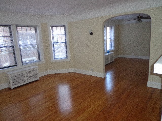 an empty living room with a wood floor and windows