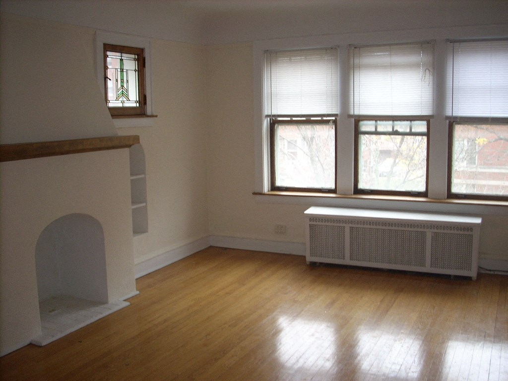 an empty living room with a fireplace and three windows
