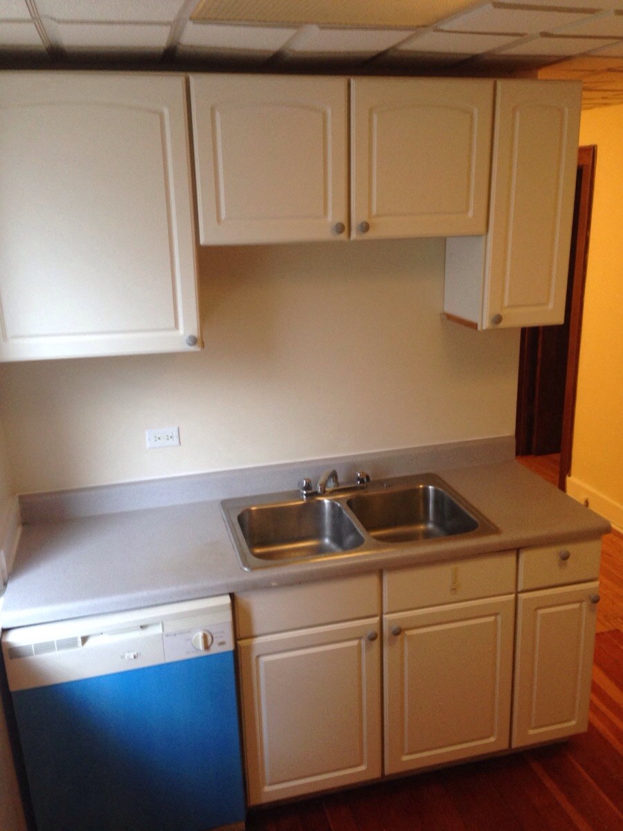 a kitchen with white cabinets and a sink and a dishwasher