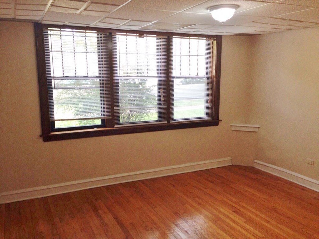 an empty room with a window and wooden floors
