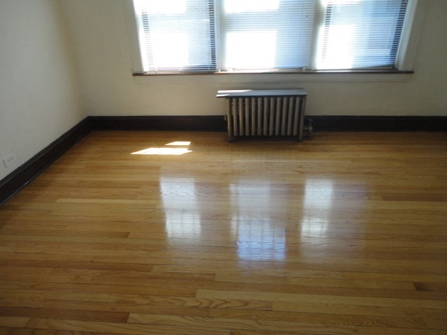 a living room with wooden floors and a window and a radiator