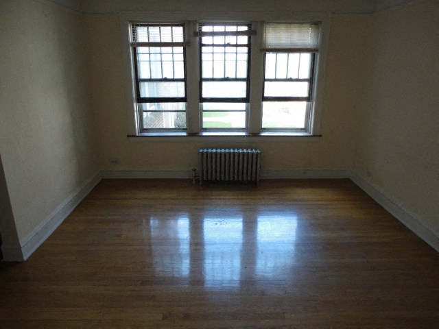 an empty room with wooden floors and three windows