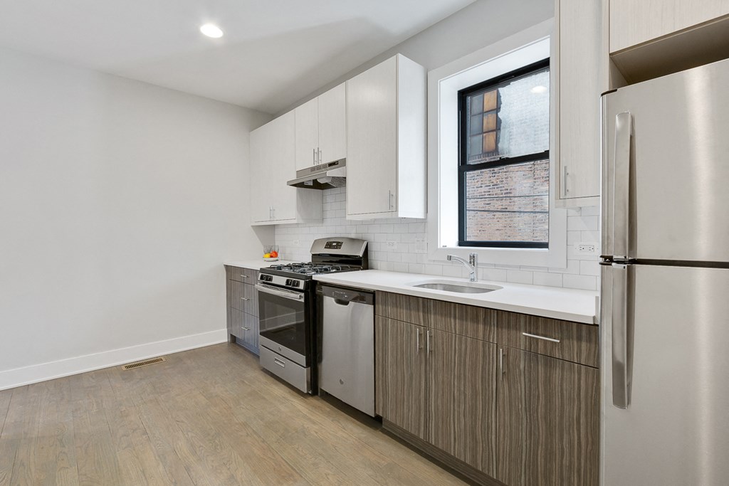 a kitchen with white cabinets and a window and a stainless steel refrigerator