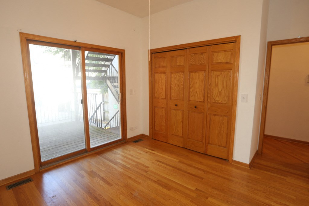 an empty living room with wooden floors and a door to a balcony