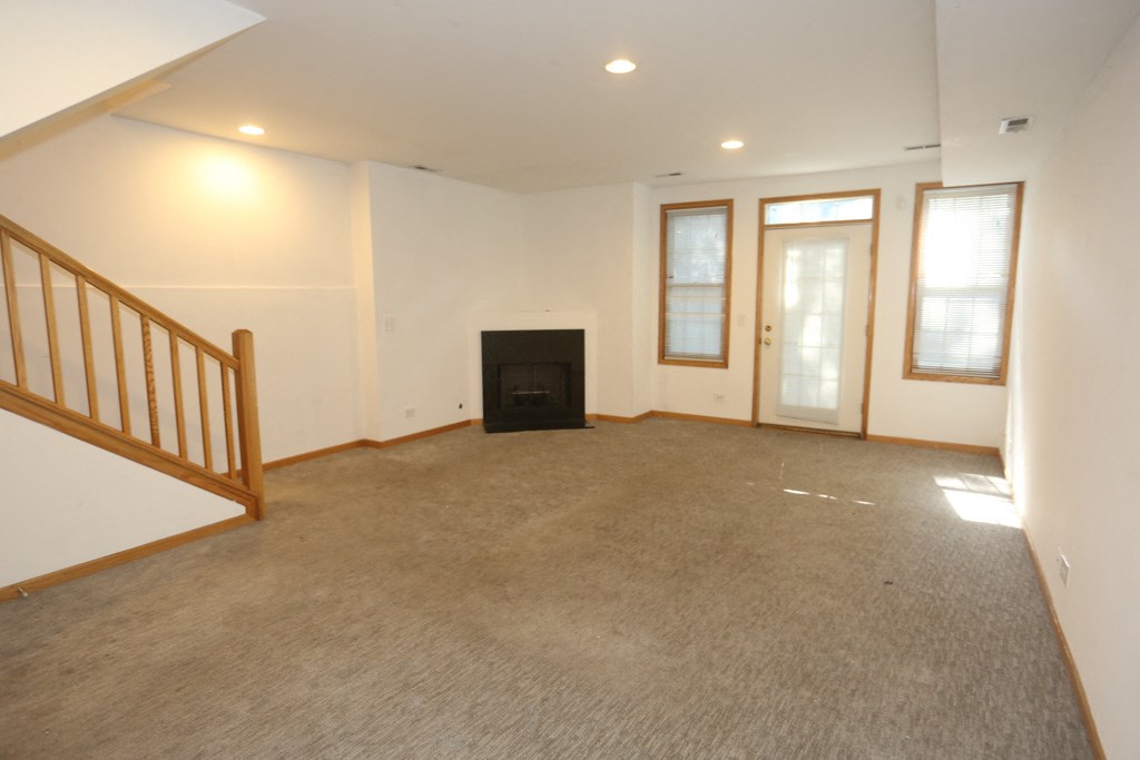 an empty living room with a fireplace and a staircase
