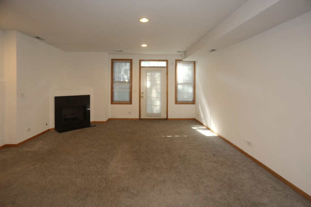 an empty living room with a fireplace and white walls