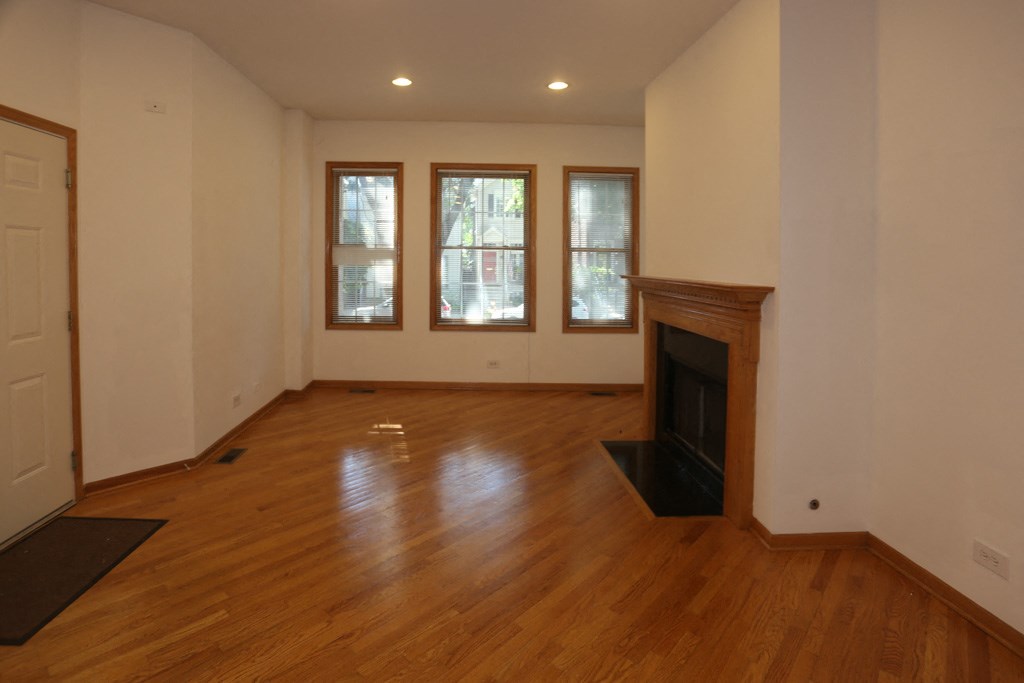 an empty living room with a fireplace and wooden floors