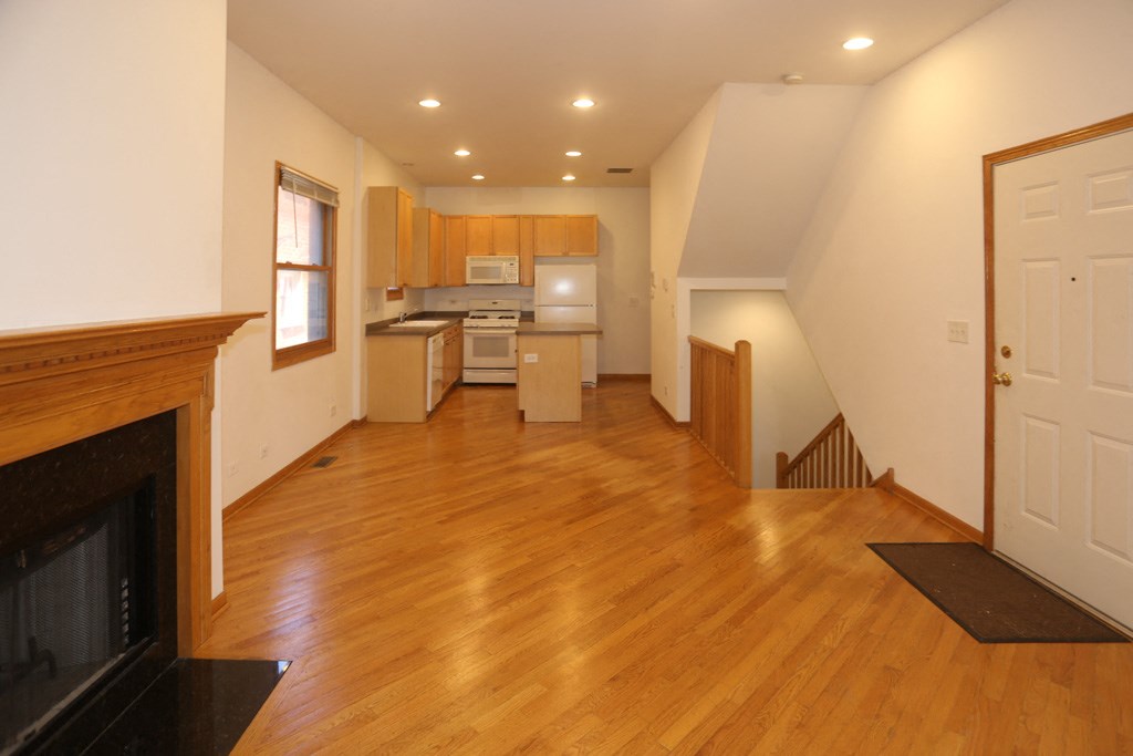 an empty living room with a fireplace and a kitchen