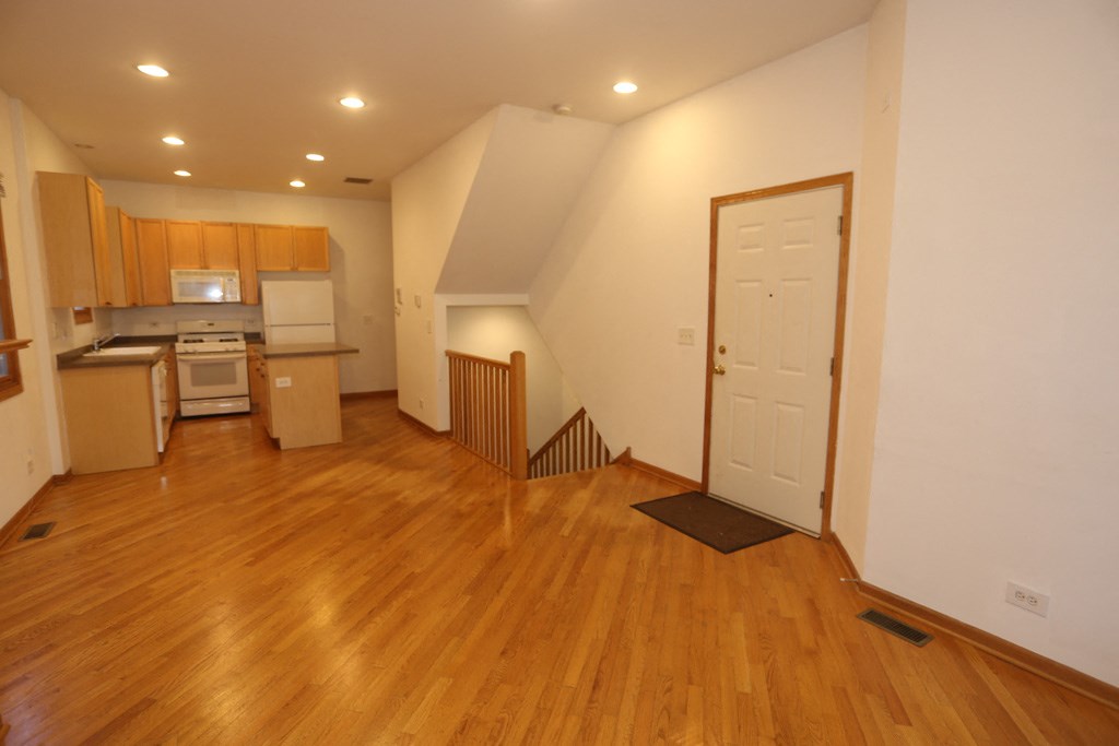 a view of an empty living room and kitchen with wood floors