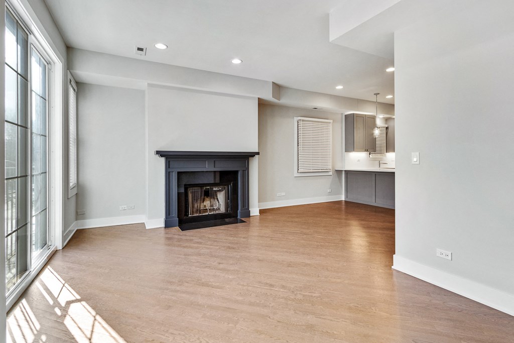an empty living room with a fireplace and a kitchen