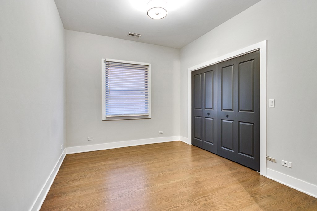 an empty living room with a black door and wood flooring