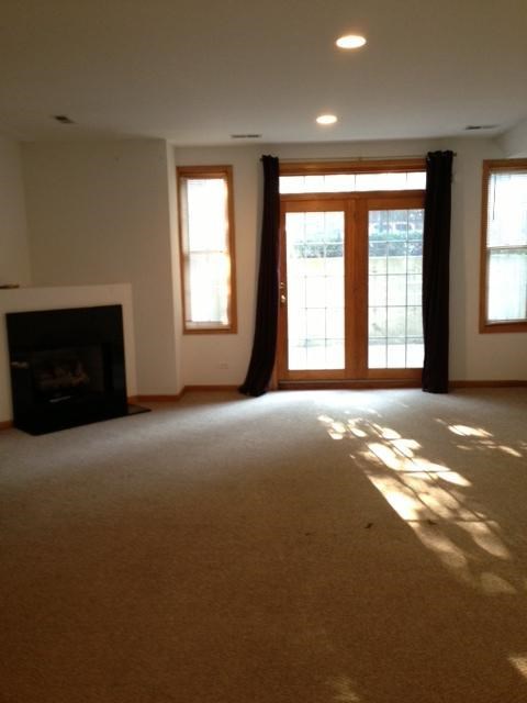 an empty living room with a fireplace and doors