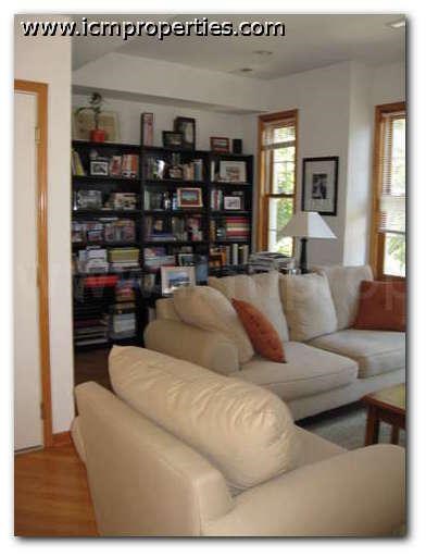 a living room with a white couch and a book shelf