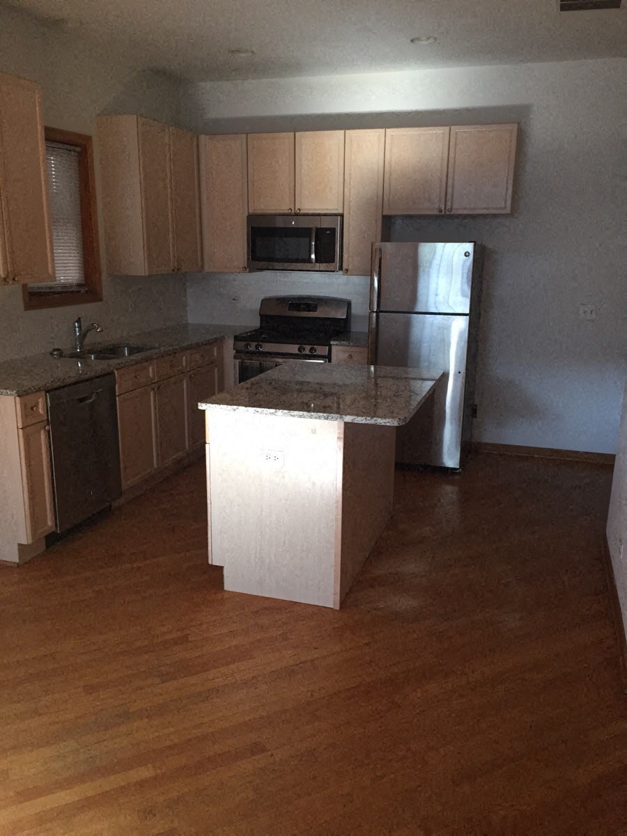 an empty kitchen with wooden floors and a refrigerator
