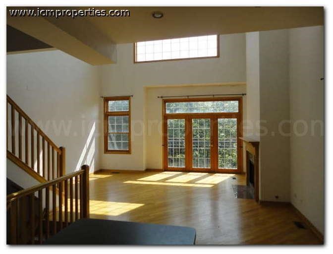 a large empty living room with wood floors and a window
