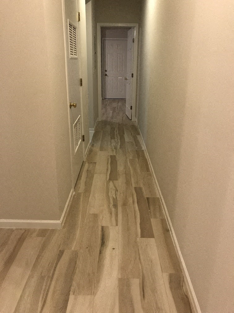 a hallway with wooden floors and a white door