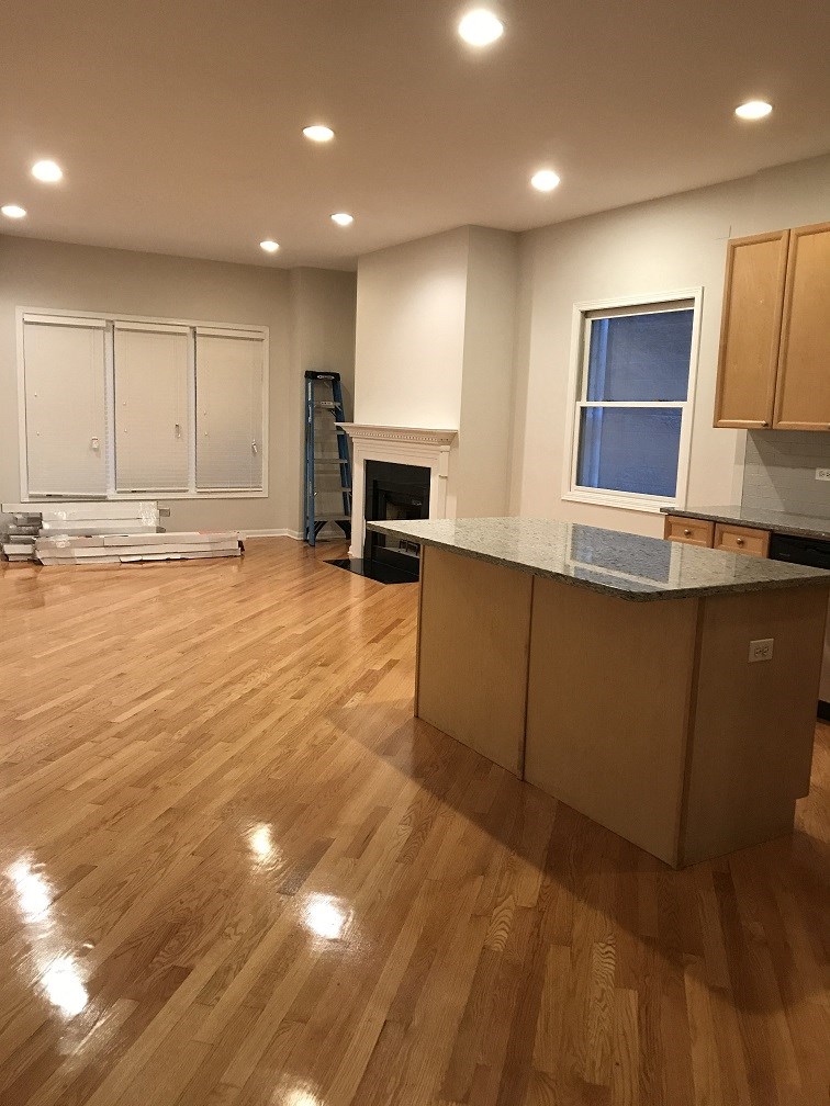 an open kitchen and living room with hardwood floors and a fireplace