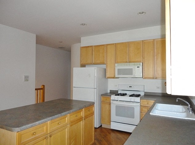 an empty kitchen with white appliances and wooden cabinets