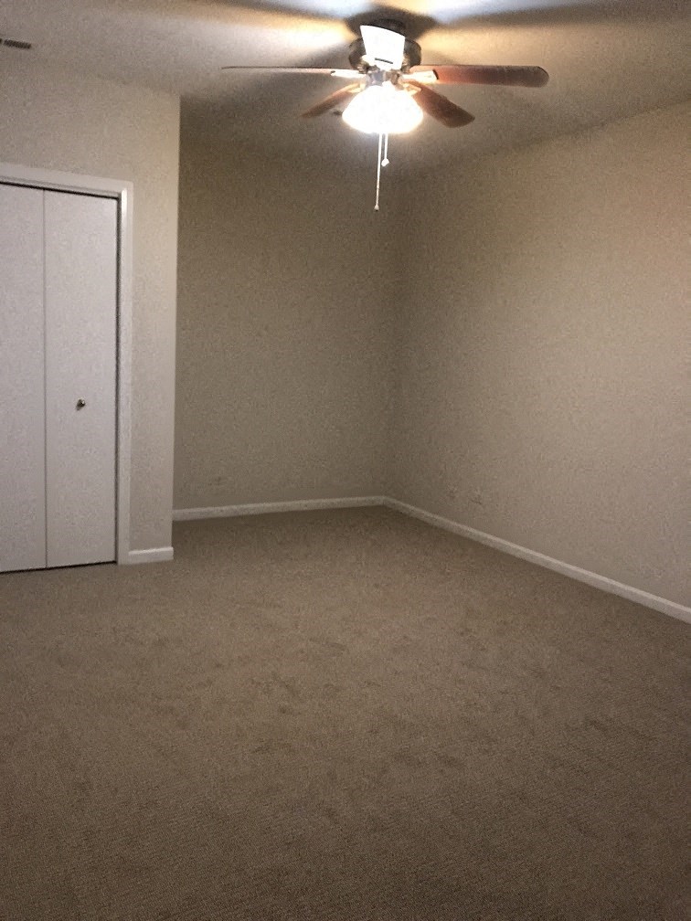 an empty room with a ceiling fan and a door