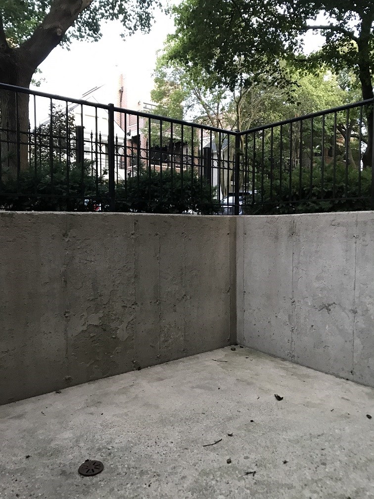 a cement wall with a black fence and trees