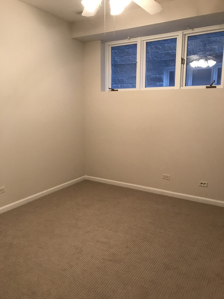 an empty room with two windows and a carpet