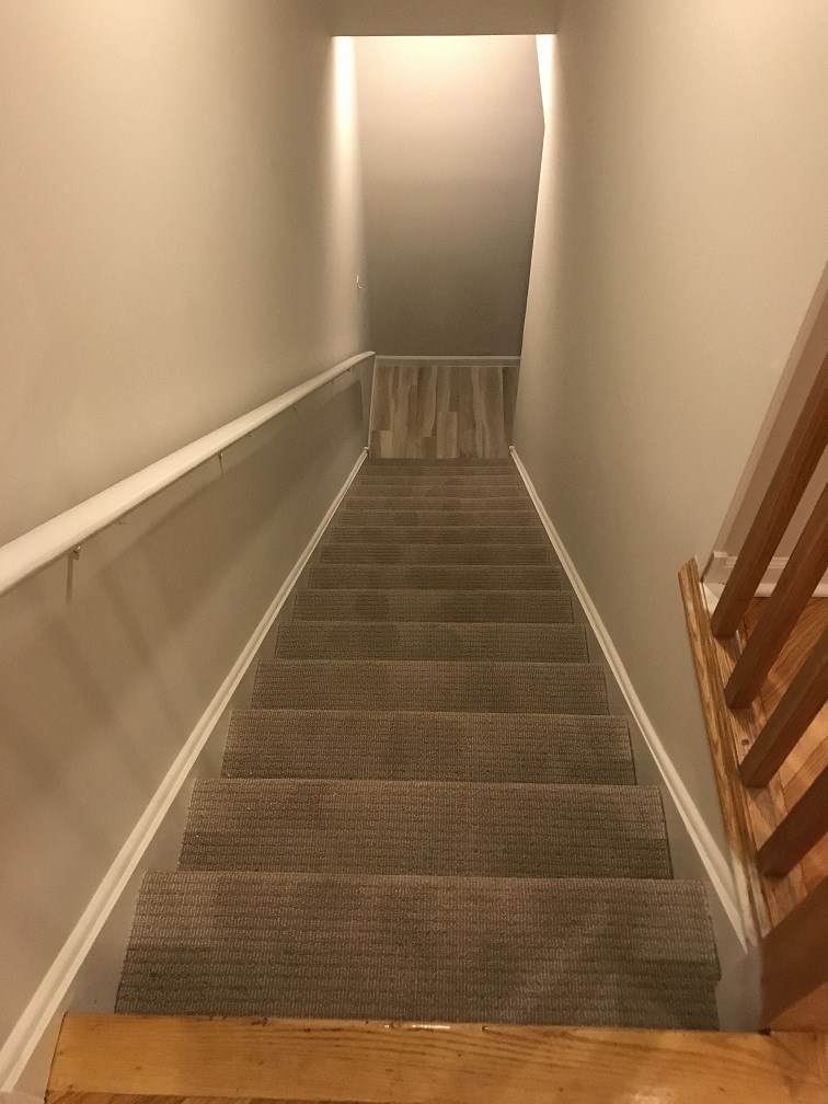 a set of stairs leading up to a hallway with white walls and wood floors