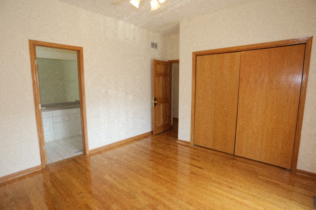 an empty living room with wooden floors and a door to a bathroom