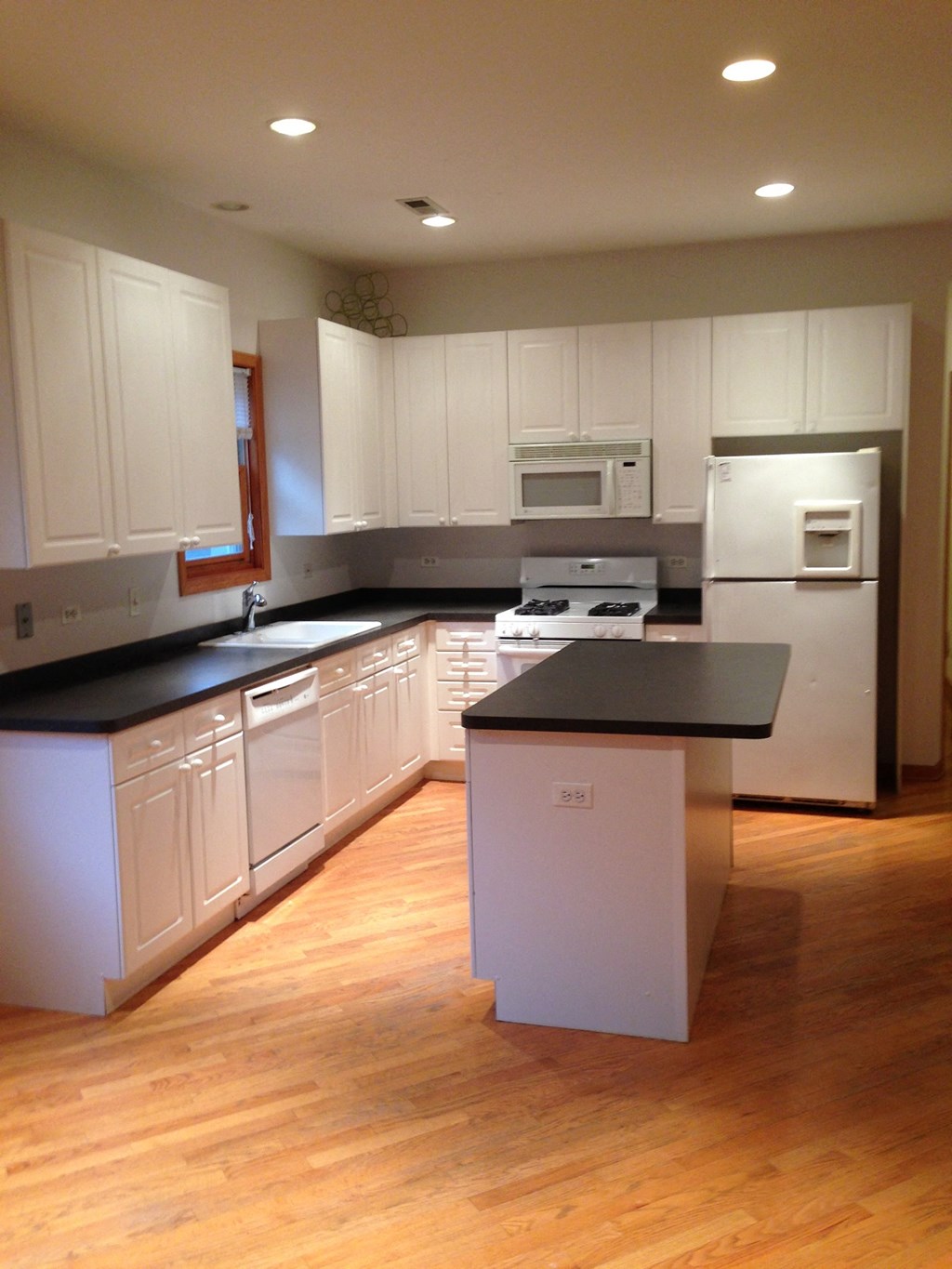 an empty kitchen with white cabinets and a black counter top