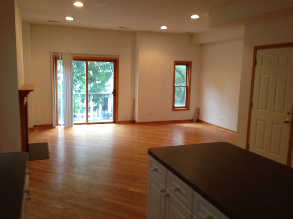an empty kitchen and living room with wood floors and white walls