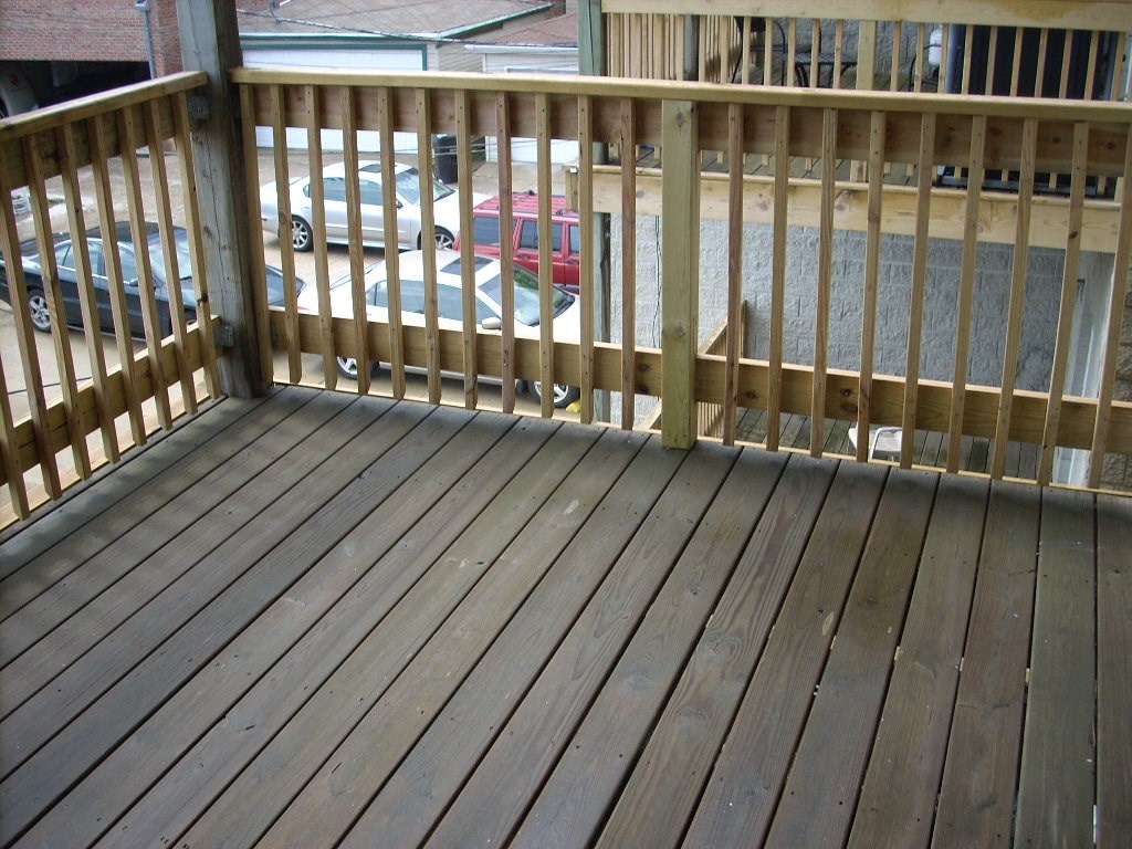 a deck with a wooden railing and a street in the background