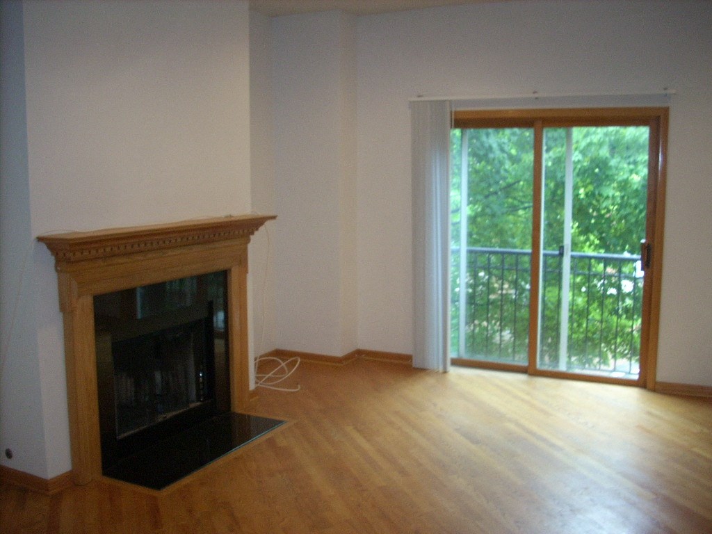 an empty living room with a fireplace and a sliding glass door