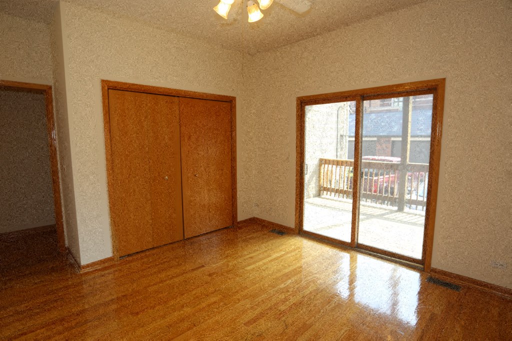 an empty living room with wood floors and a door to a balcony