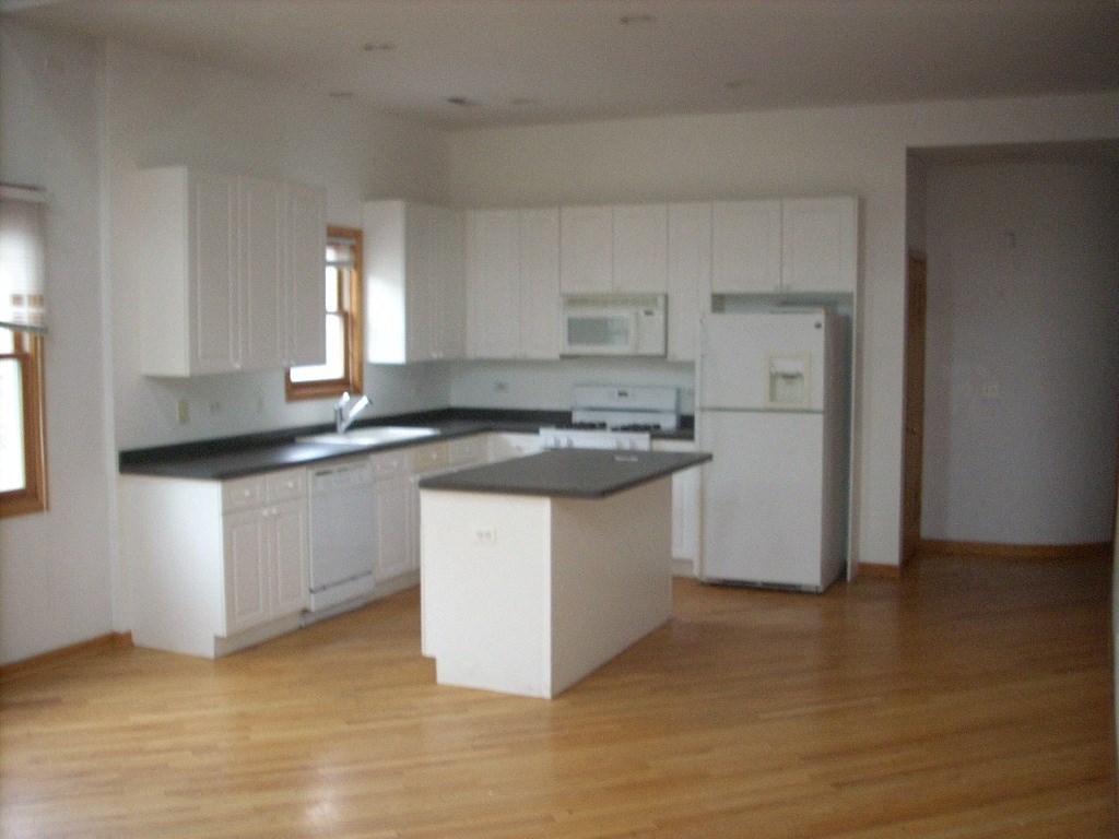 an empty kitchen with white cabinets and a counter top