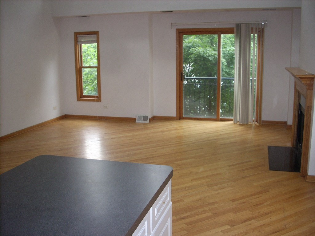 an empty kitchen and living room with wood flooring and windows