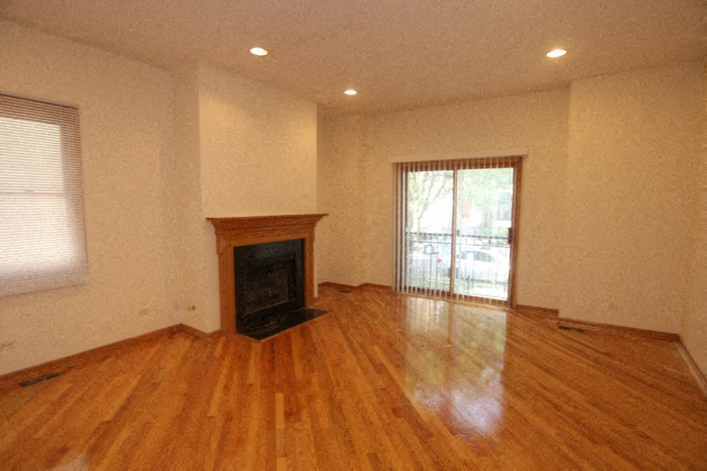 an empty living room with a fireplace and wooden floors