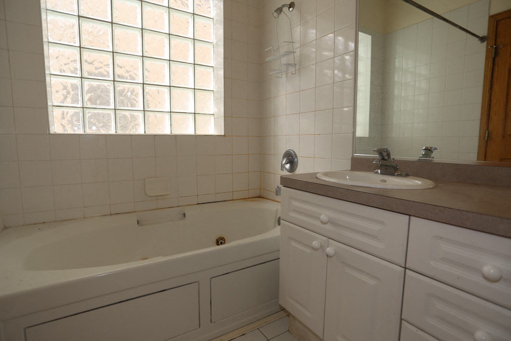 a bathroom with a tub and a sink and a mirror