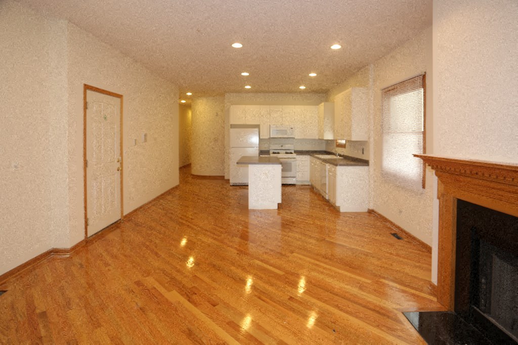 an empty living room and kitchen with wood floors