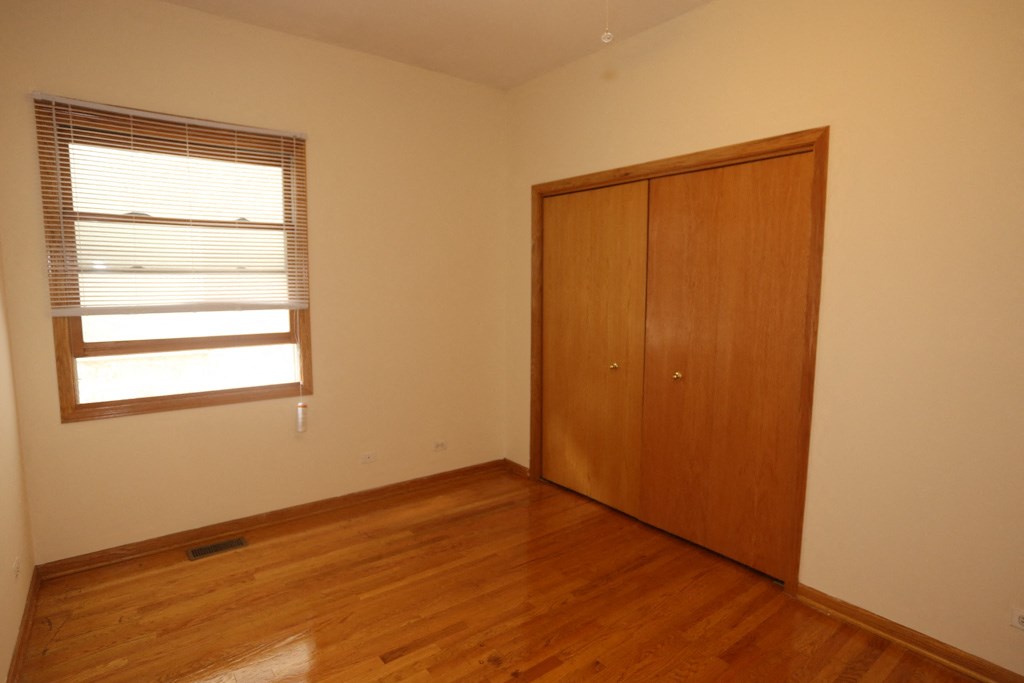a bedroom with wood floors and a closet and a window
