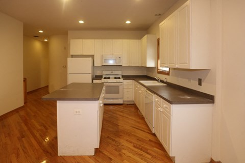 a kitchen with white cabinets and a wooden floor