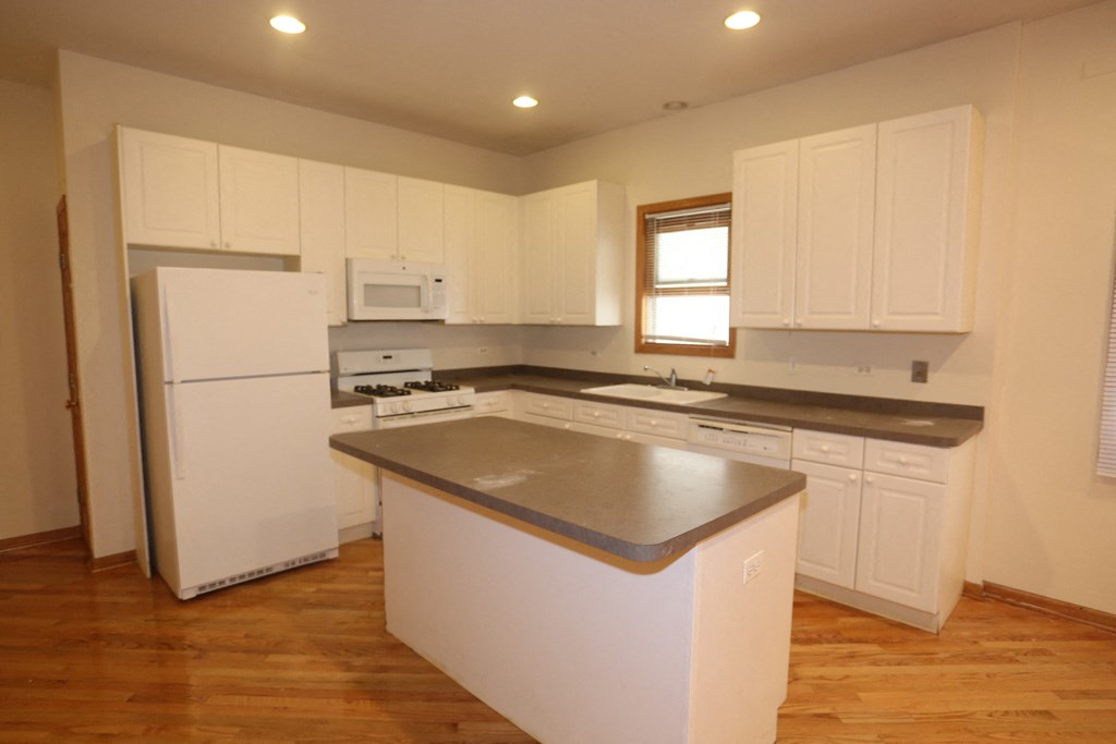 an empty kitchen with white cabinets and a counter top