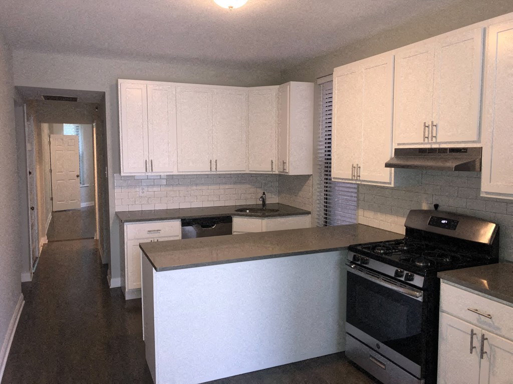 an empty kitchen with white cabinets and a stove