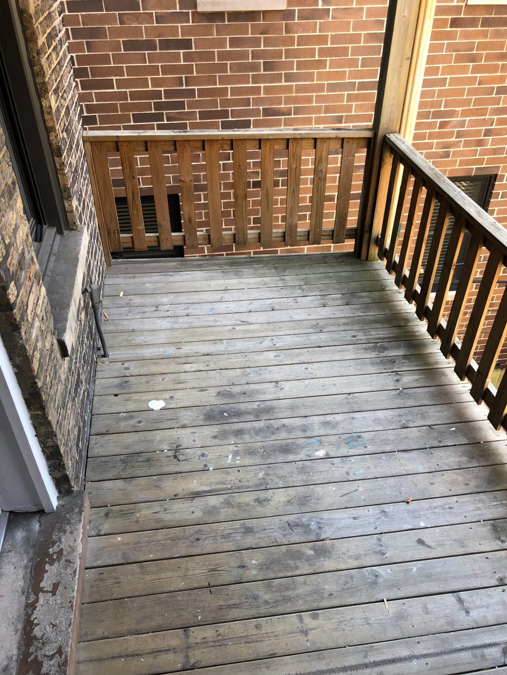 an old wooden porch with a brick wall and a wooden railing