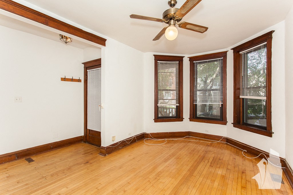 an empty living room with wood floors and a ceiling fan