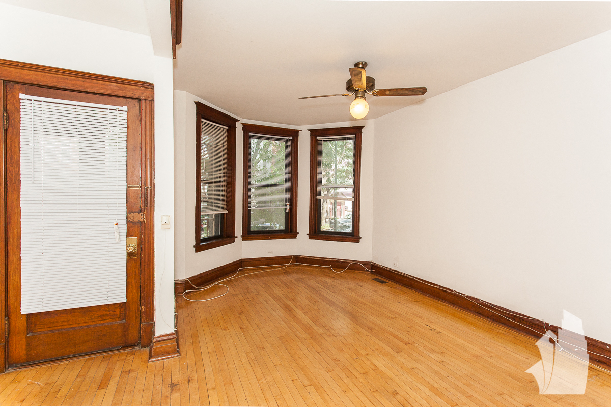 an empty living room with wood floors and a ceiling fan