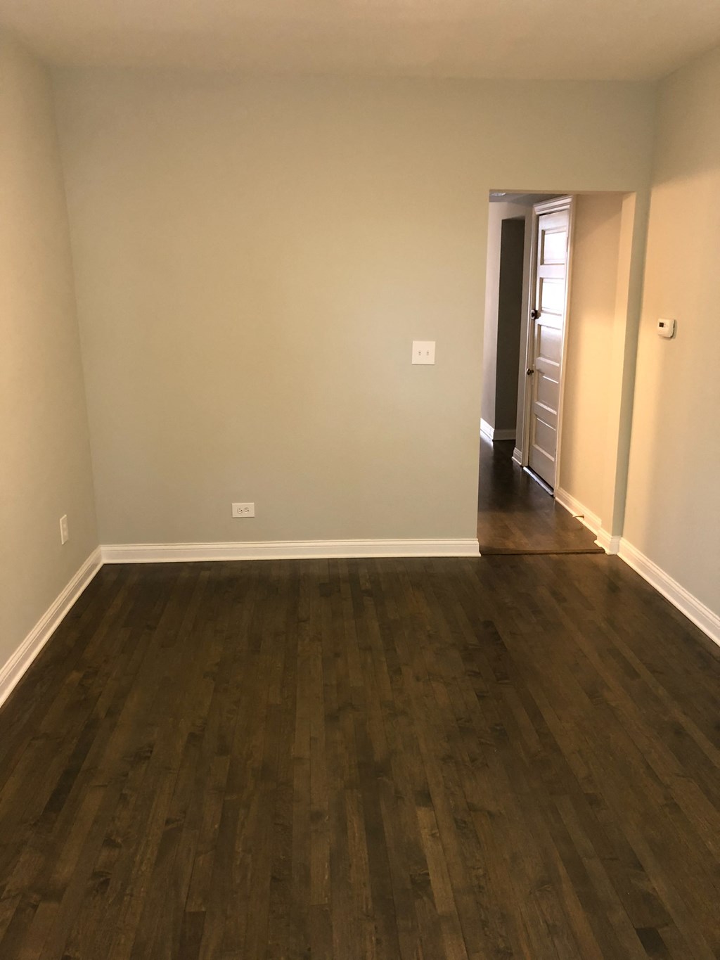 an empty living room with wooden floors and white walls