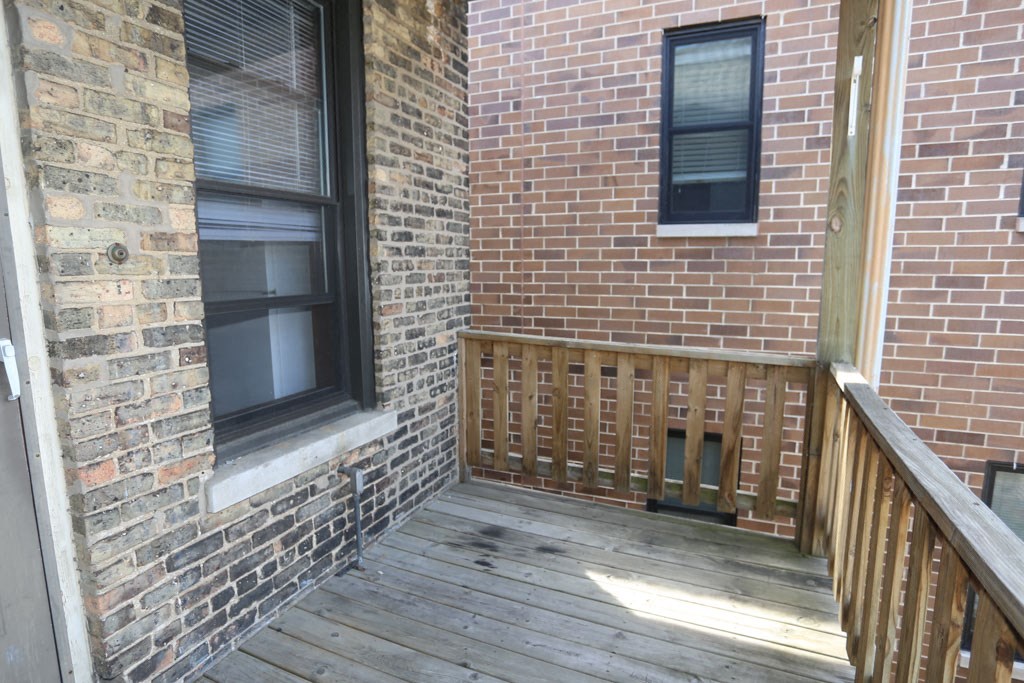 a porch with a brick wall and a wooden deck