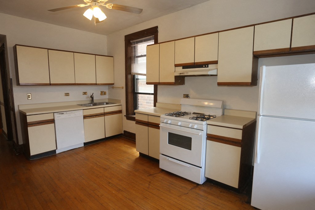 an empty kitchen with white appliances and white cabinets