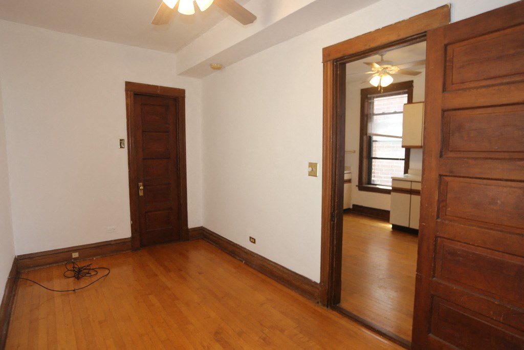 an empty living room with wooden floors and a door to a bedroom